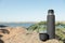 Modern black thermos on stone near river. Space for text