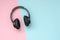 Modern black wireless headphones on a pink and blue background. The concept of music and fashion