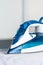 Modern blue steam iron on ironing board