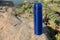 Modern blue thermos on stone near river. Space for text