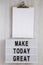 Modern board with `Make today great` words, clipboard with blank sheet of paper on a white wooden background, top view