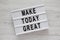 Modern board with `Make today great` words on a white wooden background, top view. Overhead, from above. Flat lay