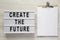 Modern board with text `Create the future`, clipboard with sheet of paper on a white wooden table, top view. From above, flat la