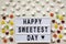 Modern board with text `Happy Sweetest Day` word and candy over white wooden surface, top view. From above, flat lay