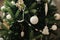 Modern boho christmas tree ornaments, white baubles, wooden garland, christmas lights close up. Atmospheric festive decorated