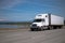 Modern bonnet white big rig semi truck with semi trailer driving