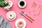 Modern breakfast desing with sweet donut, coffee and flowers on woman pink desk background top view