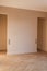 Modern and bright interior of empty cream-colored room with herringbone parquet floor