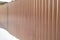 Modern brown metal corrugated siding fence, outdoor winter space, safety and security, veneer texture
