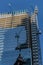 Modern building under construction at a bright sunny day on the blue sky background. Reflection of tower cranes on windows mirror