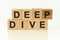 Modern business buzzword - deep dive. Top view on wooden table with blocks