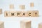 Modern business buzzword - impact. Word on wooden blocks on a white background