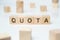 Modern business buzzword - quota. Word on wooden blocks on a white background