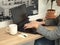 Modern business caucasian unrecognizable woman writing on her laptop with a cup of coffee, notes and a pen on her desk