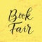 Modern calligraphy lettering of Book Fair in black on yellow textured background