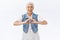 Modern, carefree charming old lady, senior woman showing heart sign and laughing, smiling joyfully, express care