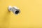 Modern CCTV security camera on yellow wall
