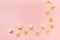 Modern celebration background with golden stars and lights on pastel pink color, top view, copy space, frame.