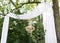 Modern celebration outdoor decoration. Destination elopement festive concept. Wedding arch made of white cotton fabric, decorated