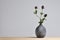 Modern ceramic vase with thistle flower on gray background