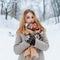 Modern charming young girl in a vintage warm coat in beautiful woolen mittens with a fashionable scarf with a red pattern
