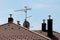 Modern chimneys with new shiny metal pipes on top surrounding tall metal pole with multiple TV antennas on top of family house