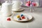 Modern chocolate candy on white plate and white teapot on white table