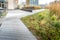 Modern city landscaping with wooden walkways, green plants and flower near modern office building