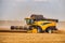 Modern Combine Harvester With a Large Mower in a Wheat Field. Agricultural Seasonal Work