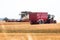 Modern combine harvests a wheat field near a tractor with a trailer