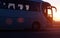 Modern comfortable passenger bus against the background of the orange sky with sunset rides on the highway. The concept of travel