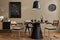 Modern composition of dining room interior with design wooden table, stylish chairs, decoration, teapot, cups, vessel, commode.