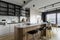 Modern composition of kitchen interior with kitchen island, stylish black chockers, built-in kitchen, glass cabinets, grey table