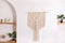 Modern composition of wabi sabi interior with shelf with home decoration and macrame.