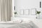 Modern cozy bedroom with white linen and a white wall with three blank posters