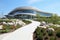 Modern, curvy architecture of a spacious office building with a landscaped pathway under a clear sky