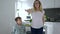 Modern dances, mother in glasses teaches son dance movements at home in kitchen