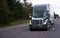 Modern dark green semi truck and trailer on straight road