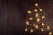 Modern decoration for festive event - glossy golden stars garland burning on brown wood plank, border, top view.