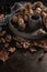 Modern design black ceramic bowl with walnuts, hazelnuts, almonds, chestnut hedgehogs on dark countertop and background. Autumn