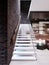 Modern design staircase in the living room, with glass railings and white independent steps on the brick wall