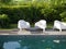 Modern design white plastic chairs at swimming pool side and outdoor garden, comfortable veranda decorated, wooden deck, back yard