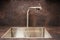 Modern designer chrome water tap over stainless steel kitchen sink
