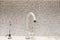 Modern designer chrome water tap over stainless steel kitchen sink. Interior of bright white kitchenÑŽ