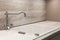 Modern designer chrome water tap over white kitchen sink