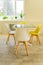 Modern dining room designed in scandi style. Glass table and yellow and white chairs