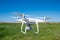 The modern drone, quadrocopter is in the air against the background of the sky and grass