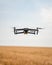 Modern drone takes flight over a vast expanse of golden wheat, highlighted by the sun