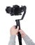 Modern dslr camera on 3-axis gimbal stabilizer with follow focus system in male videographer hands isolated on white