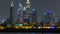Modern Dubai city skyline timelapse at night with illuminated skyscrapers over water surface
